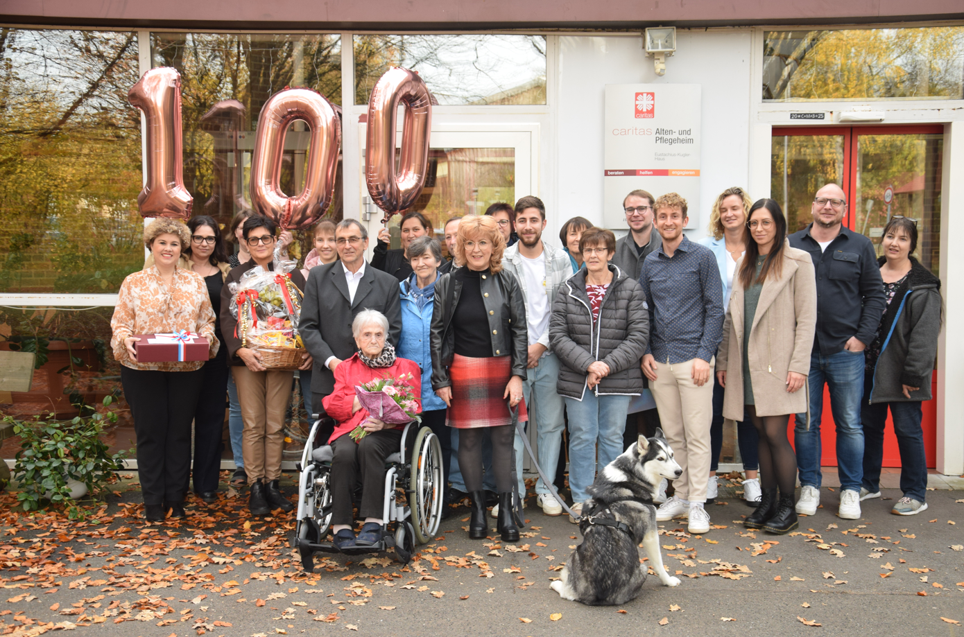 Gruppe Menschen vor Altenheim mit Ballons