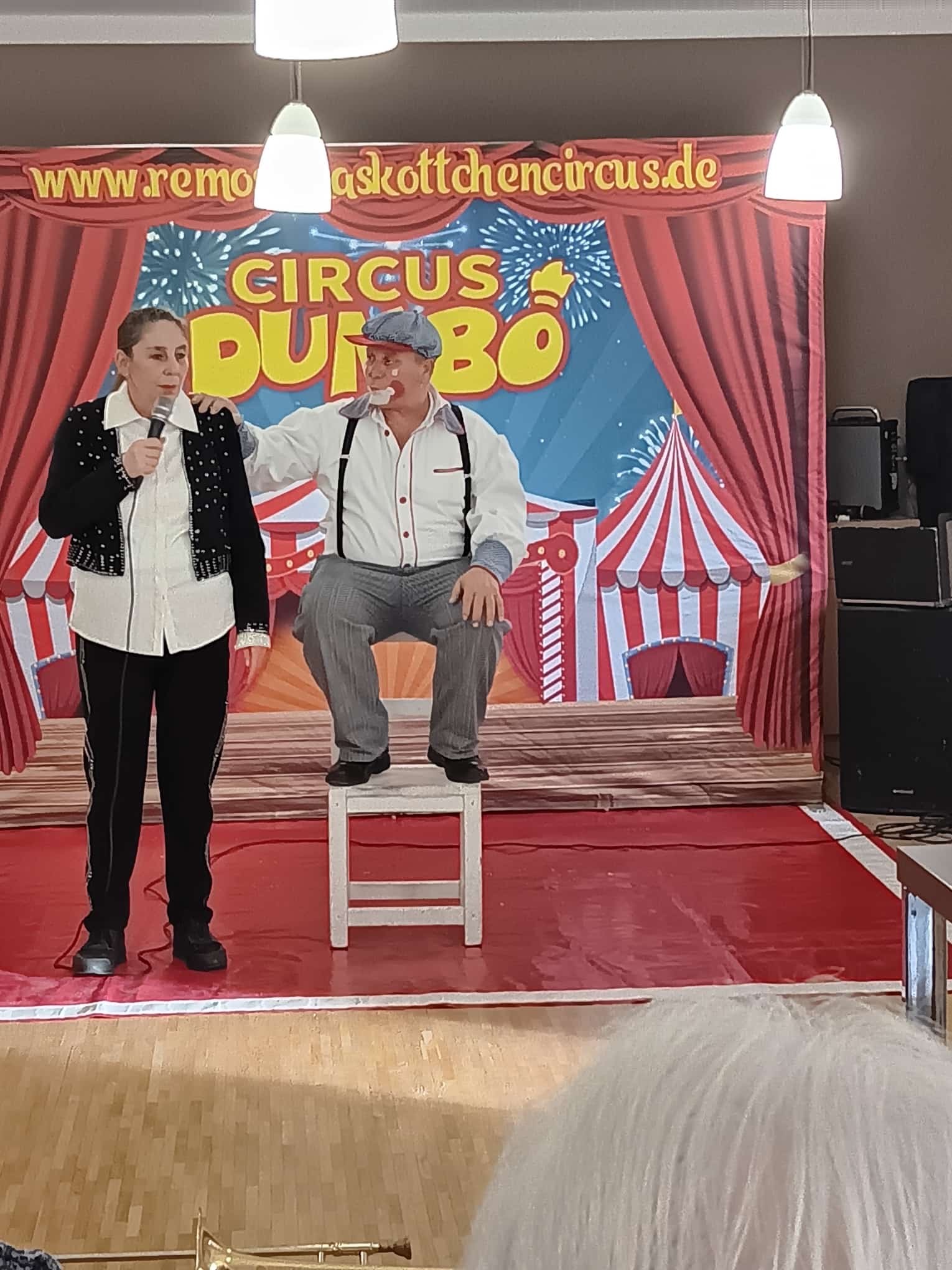 2 verkleidete Personen auf einer Bühne vor einem Zirkuszelt