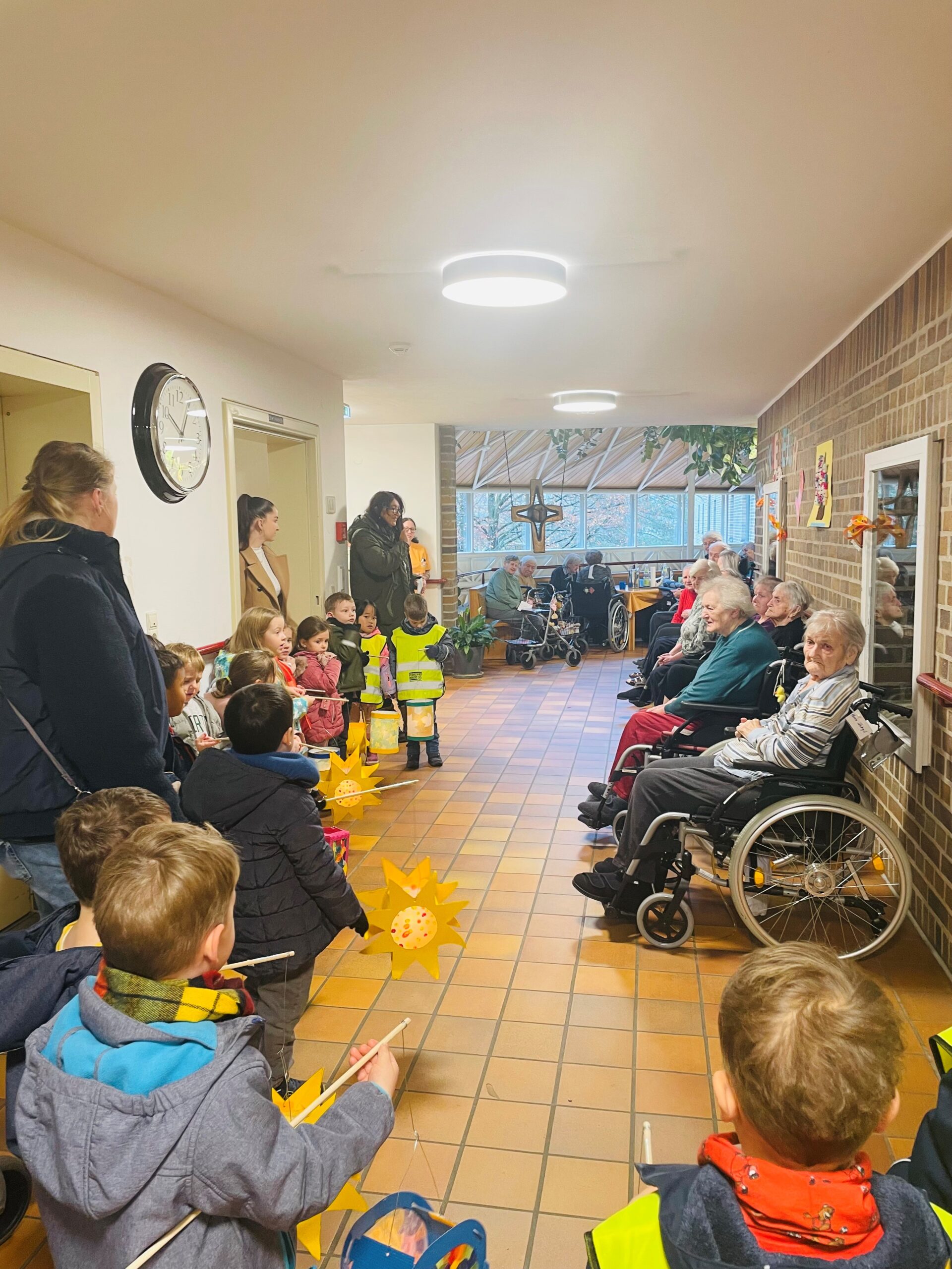 Kinder mit Laternen und Senioren in einem Gang