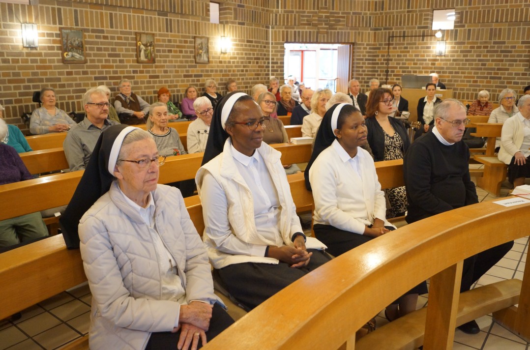 Nonnen und andere Menschen in einer Kirchenbank