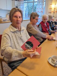 Bewohner mit Weihnachtskarten in der Hand an einem Tisch