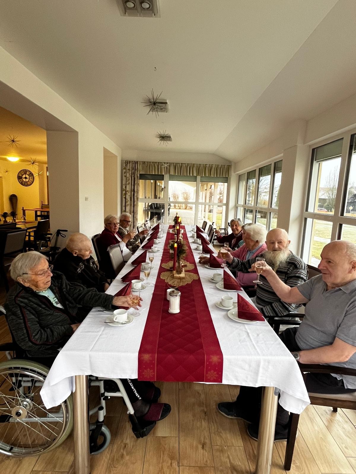 Senioren an einer festlich geschmückten Tafel in einem Altenheim