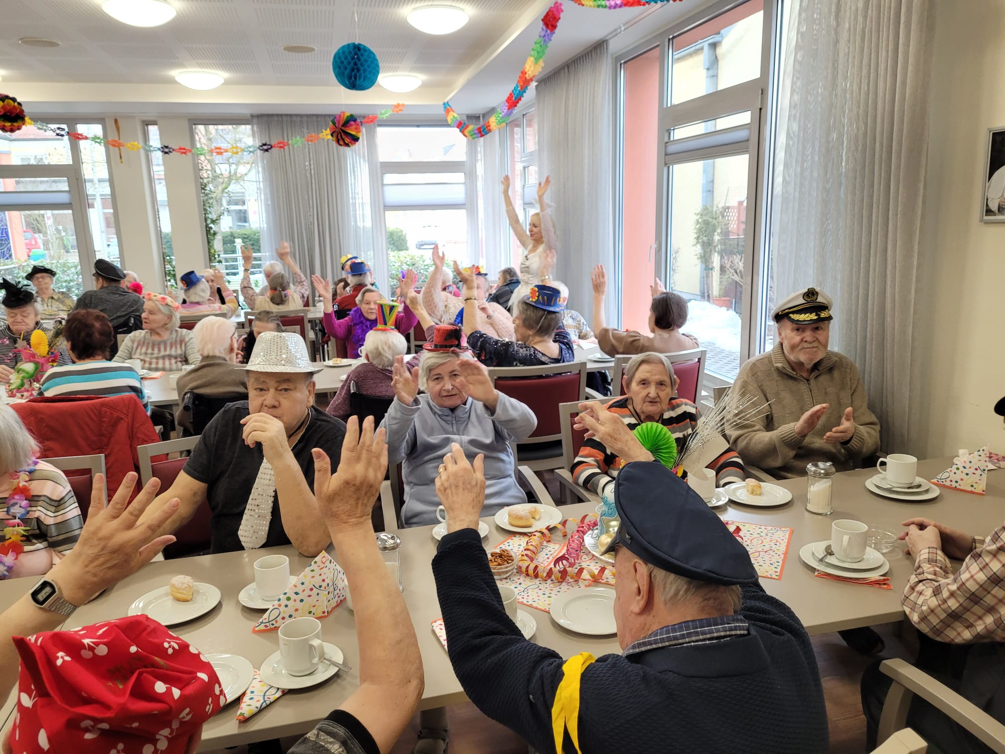 Verkleidete Senioren feiern an Tischen in einem Seniorenheim