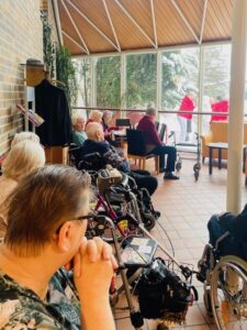 Senioren beobachten aus dem Fenster wie eine Schneefrau gebaut wird.
