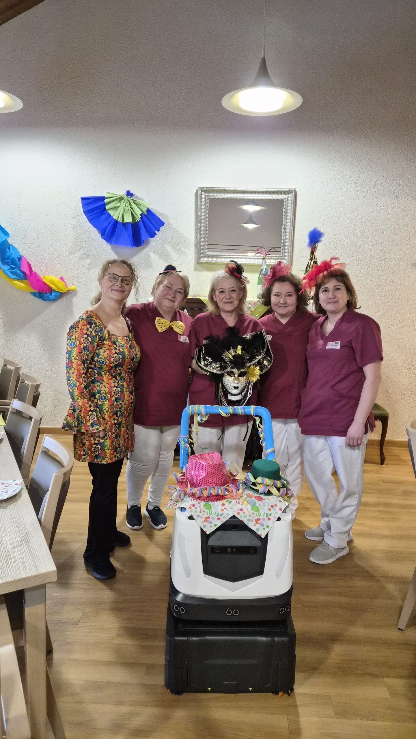 Fünf Personen hinter einem verkleideten Reinigungsroboter in einem Altenheim