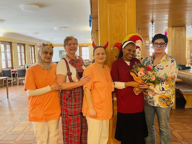 5 Personen im Portrait. Eine mit Blumenstrauß in der Hand.