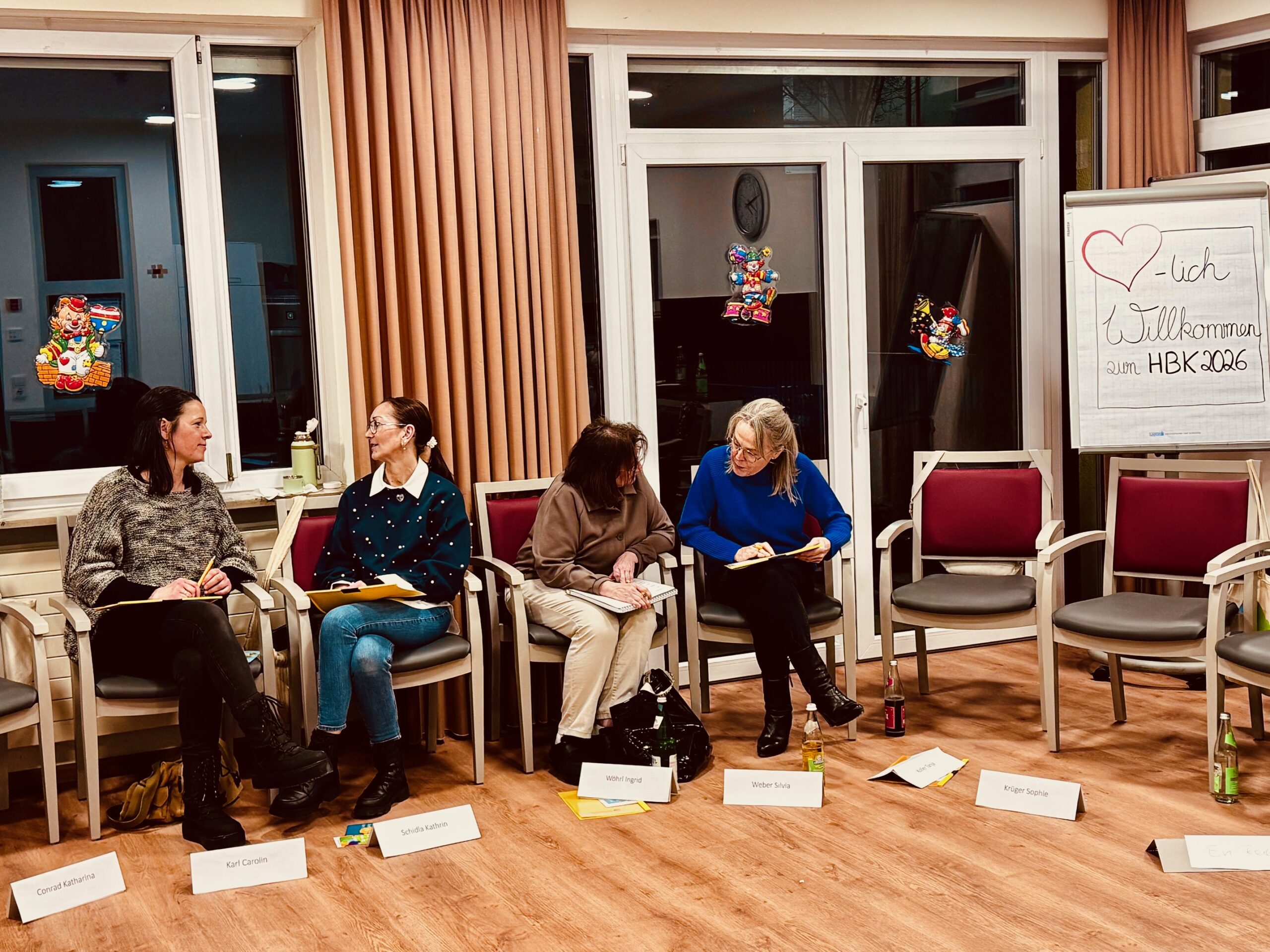 Personen unterhalten sich auf Stühlen in einem Raum.