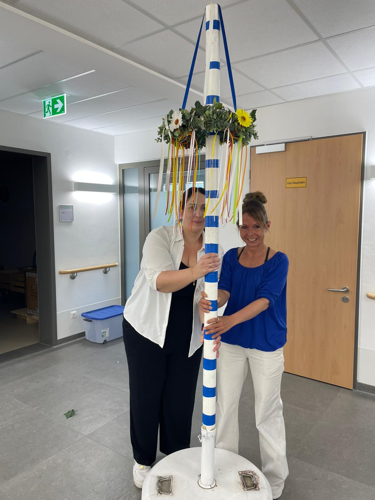 Zwei Pflegerinnen und Maibaum