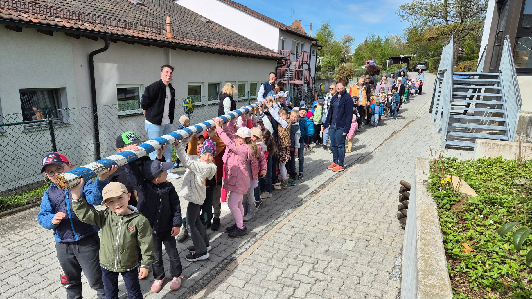 Kinder tragen einen Maibaum im Freien