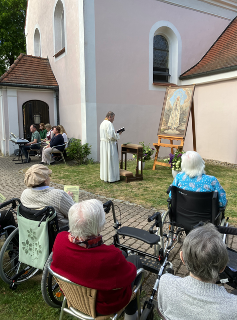 Pfarrer vor Marienbild im Freien